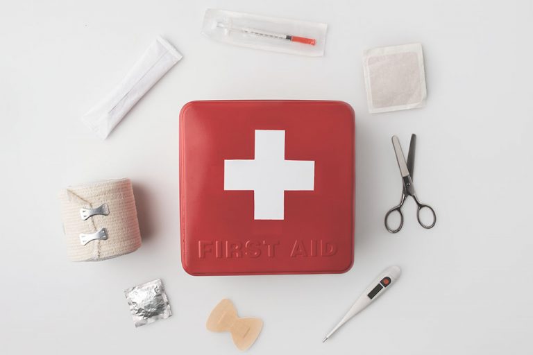 A first aid kit with medical equipment surrounding it